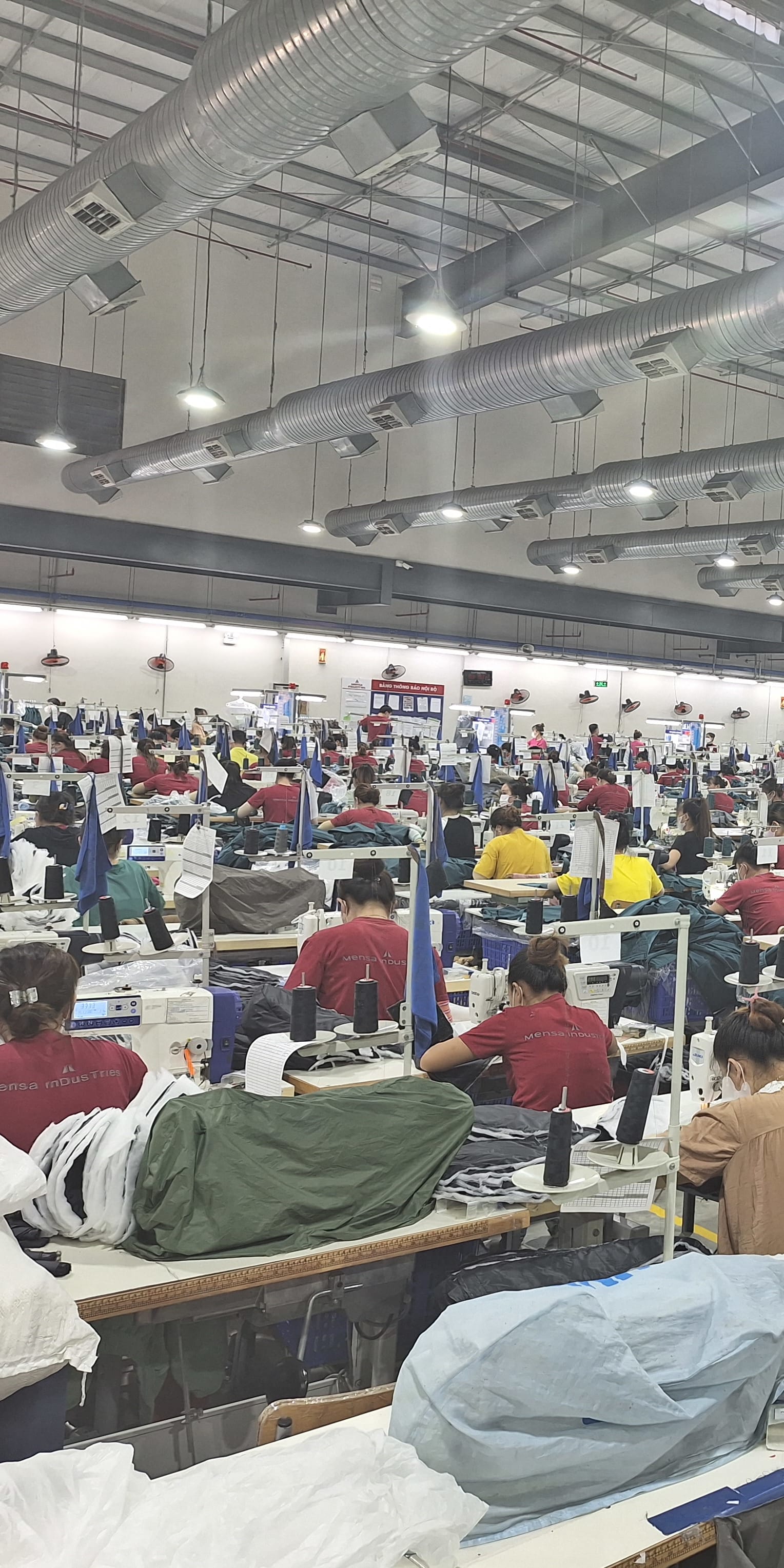 A large factory space with rows of people sewing Norrøna garments. 
