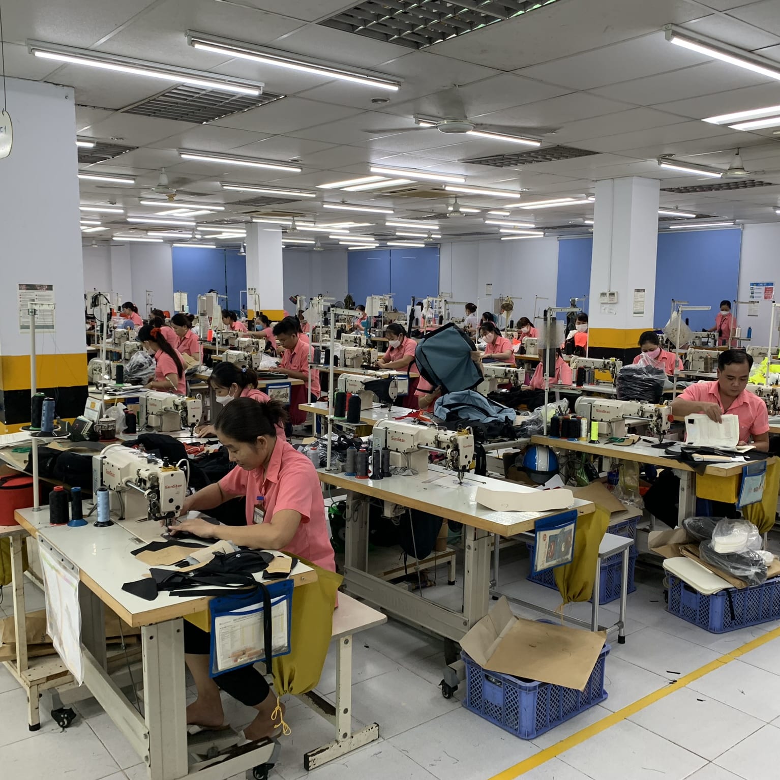 A factory floor with several people sewing Norrøna products. 
