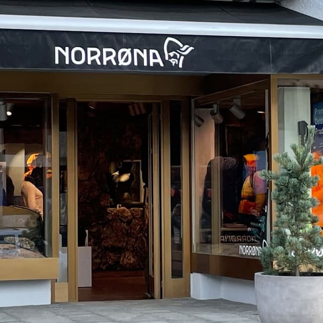 A storefront with a Norrøna sign and a display of ski gear, including clothing and skis. 

