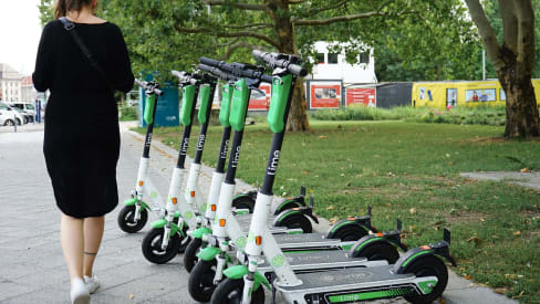 Lime electric scooters park by the sidewalk