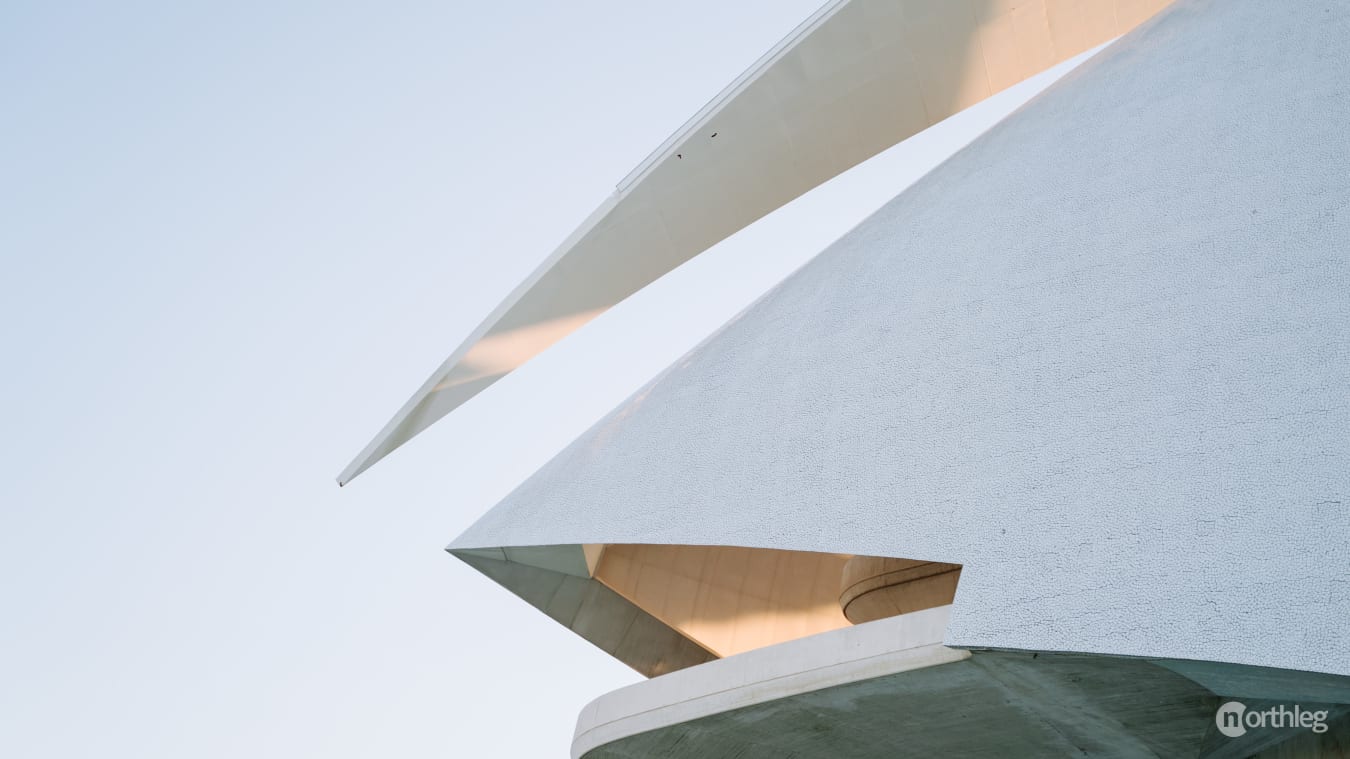 Futuristic white architectural complex with curved, organic shapes resembling a spaceship or modern art installation.