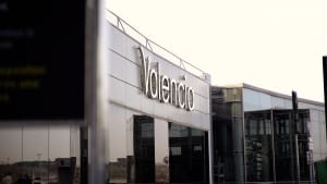 Exterior of Valencia Airport terminal with large 'Valencia' sign on modern white building with glass facade.