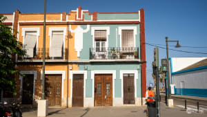 Colorful orange and green historic houses with wooden doors and balconies in Valencia's maritime district.