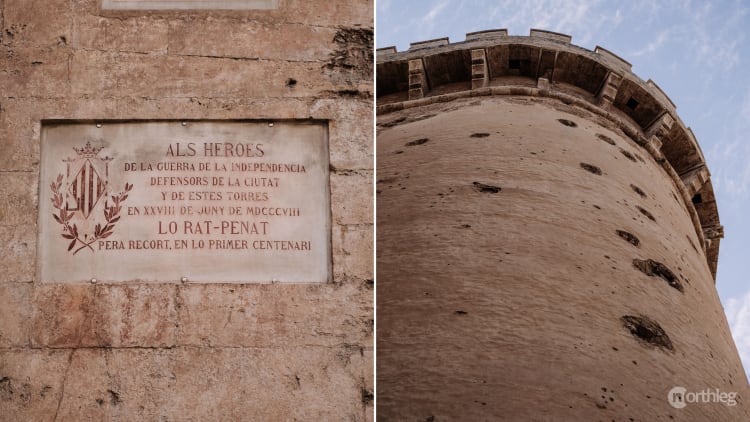 Close-up of stone memorial plaque and tower wall with multiple cannon impact marks from the Peninsular War.