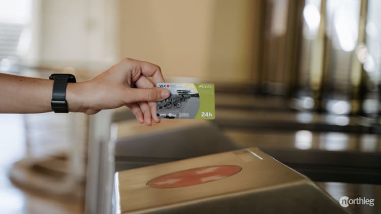 A hand holding a Valencia Tourist Card near a metro station ticket validation machine.