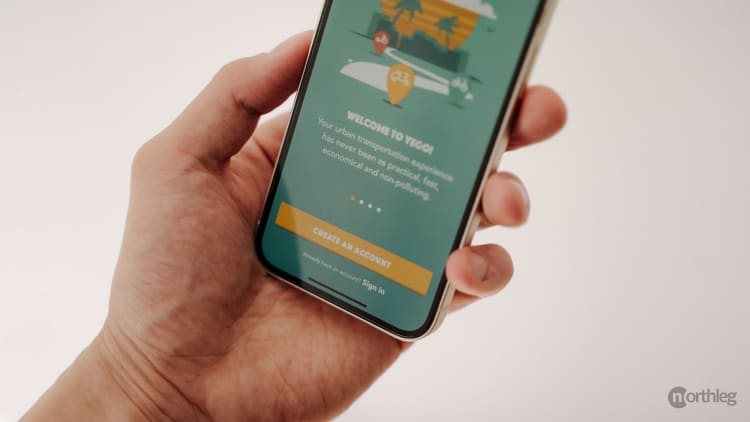 Smartphone screen displaying Yego app's account creation page with green and yellow color scheme, being held by a hand.