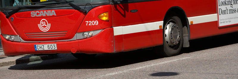 Bilden visar den främre delen av en röd buss parkerad vid sidan av en gata. Bussen har texten "SCANIA" och SL:s logotyp på fronten. Ett registreringsnummer "CHZ 603" är synligt på en skylt under fronten. Nummer "7209" är placerat under bussens vindru