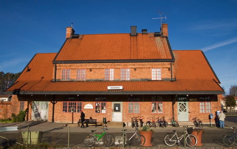 Bilden föreställer framsidan av en tegelbyggnad med ett stort tegeltak under en klarblå himmel. Byggnaden har flera fönster i två våningar på framsidan och en dörr i mitten av den nedre våningen. Ovanför entrén sitter en skylt med texten "VÅGNÄSRAD".