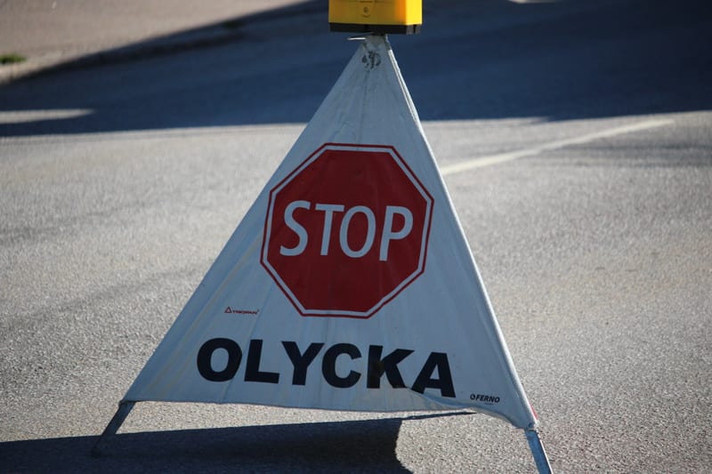 Bilden visar en portabel varningsskylt av triangulär modell placerad på en asfalterad yta, troligen en väg. Skylten har en vit yta med text i svart och rött. Överst på skylten finns ett rött stopptecken med ordet "STOP" i vitt. Under stopptecknet stå