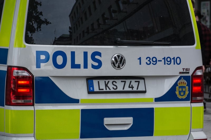 Bilden visar ett nära porträtt av bakdelen på en svensk polisbil. Fordonet är vitt med blå och limegröna reflekterande markeringar. Ordet "POLIS" är skrivet i blå versaler på bakluckan, bredvid en Volkswagen-logotyp och siffrorna "1 39-1910" även de