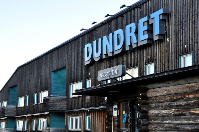 Bilden visar fasaden på en stor byggnad med texten "DUNDRET" i blåa, upphöjda bokstäver. Under den stora skylten finns en mindre skylt där det står "reception". Byggnadens övre del är klädd med mörkt trä, medan nedre delar av fasaden närmast marknivå