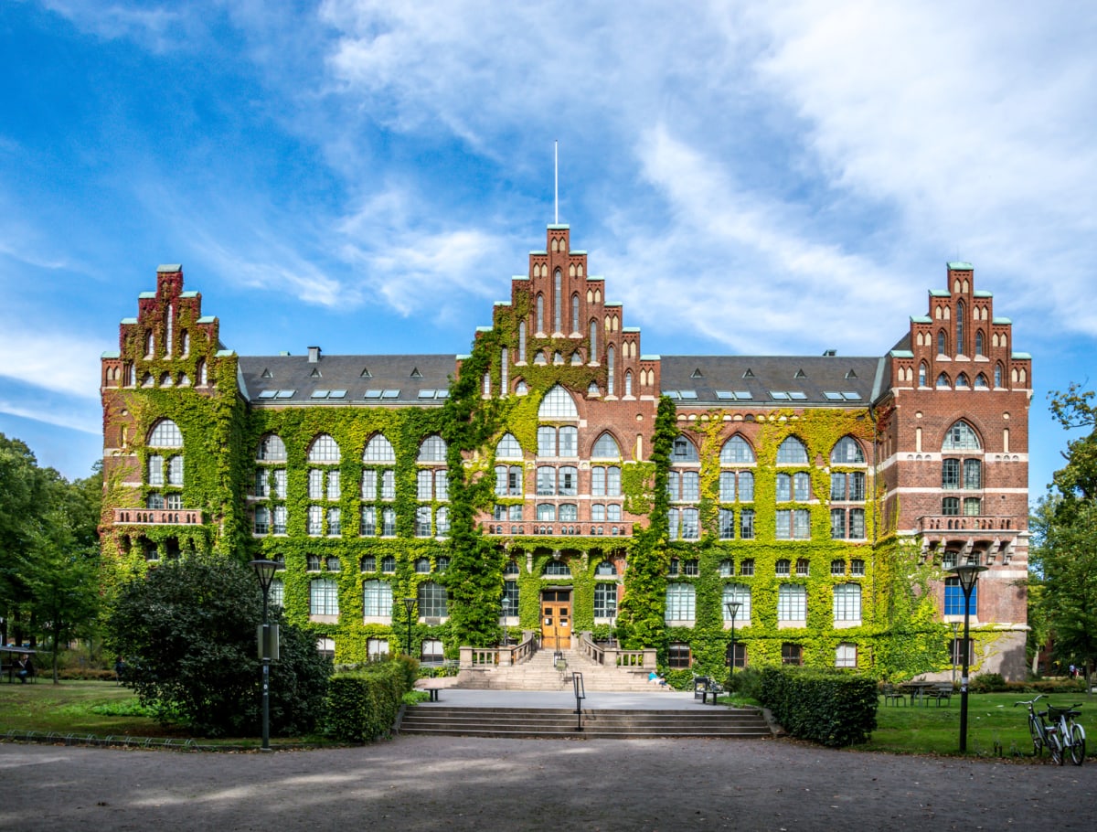 En stor, röd tegelbyggnad med ett symmetriskt mittparti med ett högt, smalt torn i mitten och två liknande torn på sidorna. Stora delar av fasaden är täckt av grön murgröna. Byggnaden har många stora fönster med välvda överdelar på de lägre våningarn
