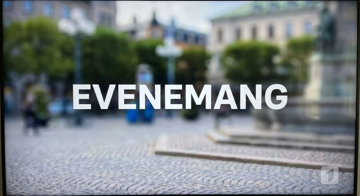 En bild av en TV-skärm som visar texten "EVENEMANG" i stora vita bokstäver mot en oskarp bakgrund. Bakgrunden föreställer en utomhusmiljö med gatsten i förgrunden, samt suddiga träd, byggnader och en staty i bakgrunden. En TV4-logotyp syns i nedre hö
