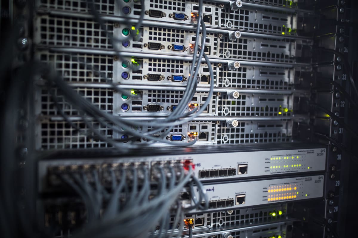 Närbild av servrar och nätverksswitchar med anslutna kablar och lysande dioder monterade i ett serverrack.