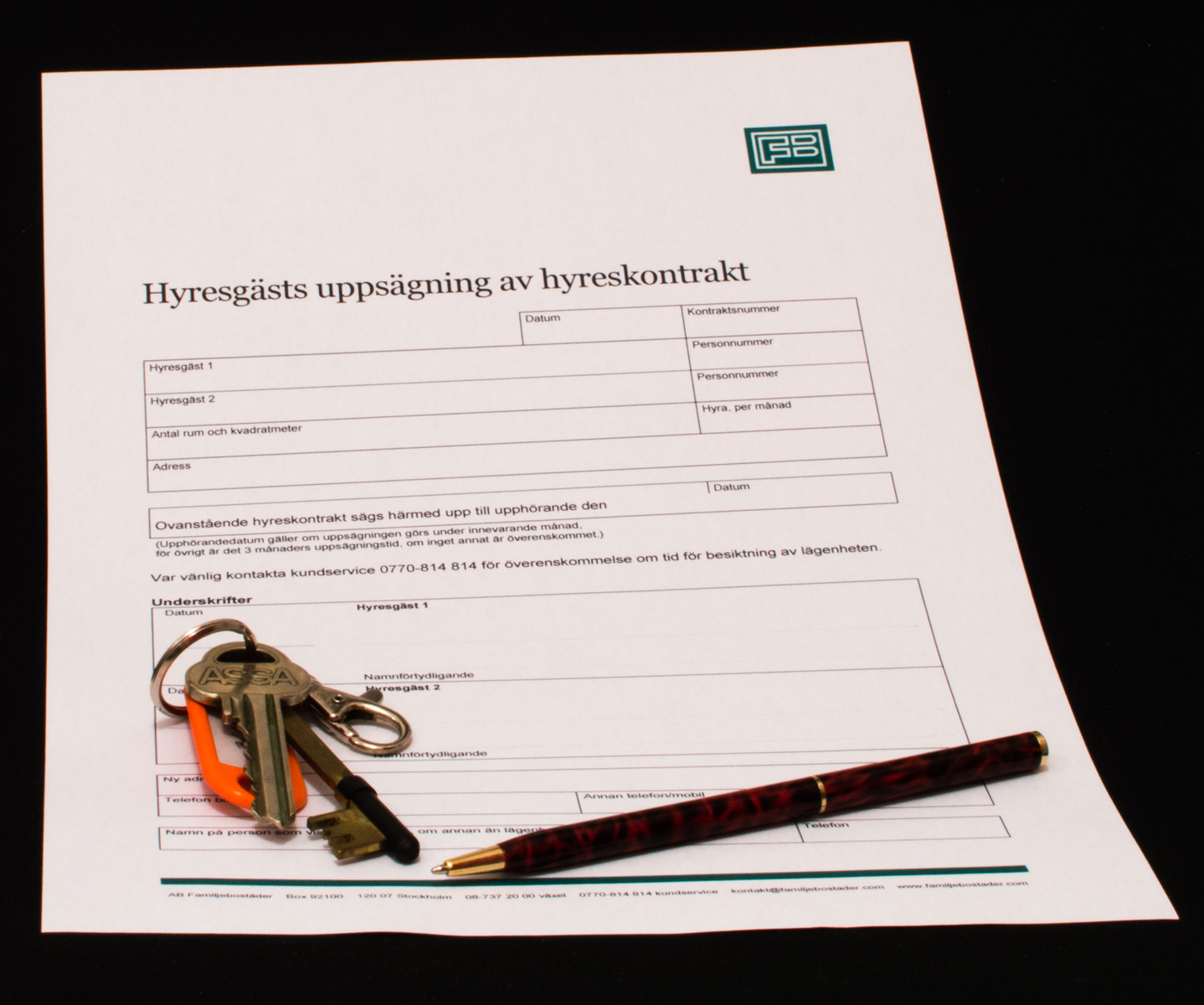 En bild som visar en utskriven blankett för "Hyresgästs uppsägning av hyreskontrakt". Blanketten ligger på en mörk yta. På blanketten syns textfält för hyresgästers information, boendedata, uppsägningsdatum och underskrifter. Ett logga med bokstävern