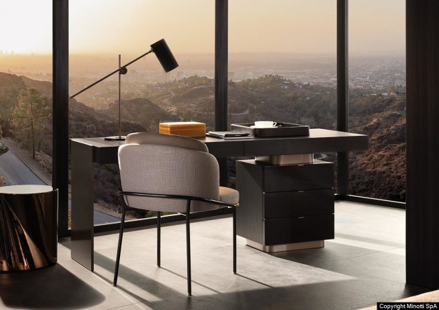 Minotti Carson bureau met MDF top en lades. Ook het interieur van de lades is MDF. Aan het bureau staal een Minotti Fil Noir eetkamerstoel in een lichte stoffering, lederen rugleuning en contrasterend onderstel. Links op de afbeelding ziet u de Minotti Noor koffietafel in het brons. 