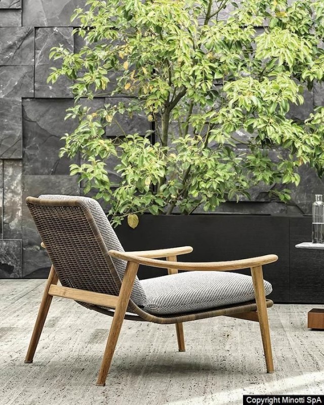 Achterzijde van de Minotti Fynn outdoor fauteuil met licht eiken houten frame, rotan achterzijden en stoffen rug en zitting.