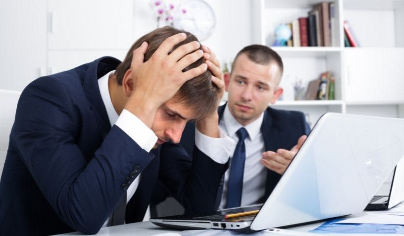 man sitting in office frustrated with laptop