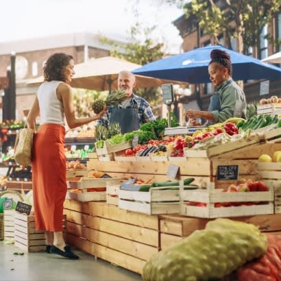 Person examines produce while shopping at farmers market