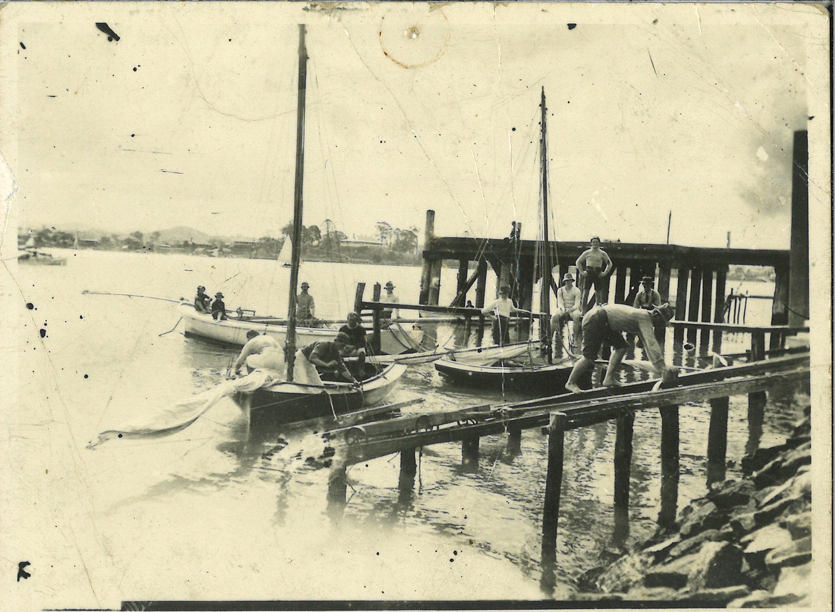 Believed to be circa 1909. The slip is at the Bulimba home of Norm's wife at Riverside Junction Quay and Brisbane Steets. We think the 3 boats are 22ft Gladys II (mast down),14ft Violet II and 10ft Commonwealth, all champions.  Climbing down slip is xxx Wright.  Standing in Commonwealth is N.R.Wright, and on the foredeck of Gladys xxx and Alex W sittig on Jetty with straw hat Lance Watts. Breeze NE (morning?)  and Newstead House in the background. Site of the future Newstead yard under mountain in background.