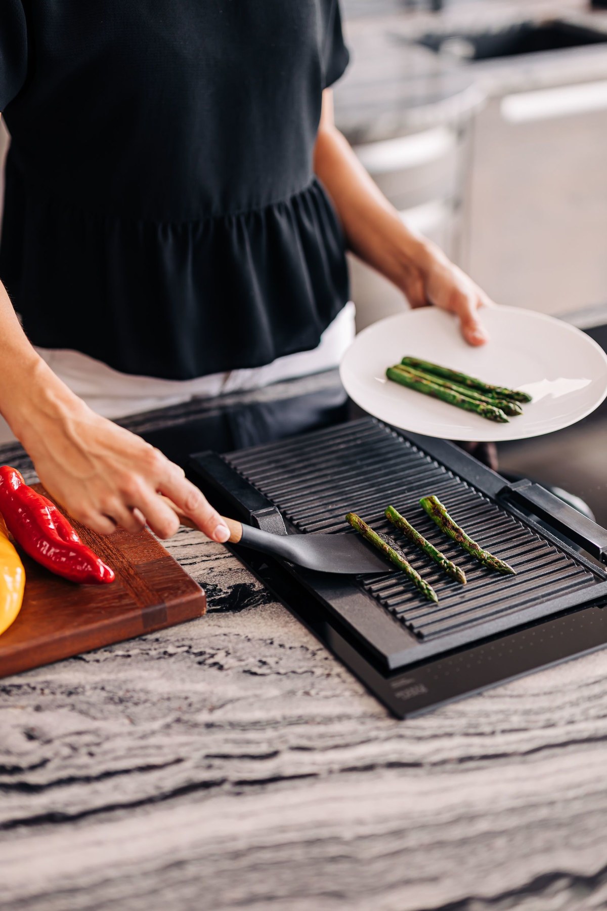 Asparagus being grilled on an induction hob with natural stone worktop