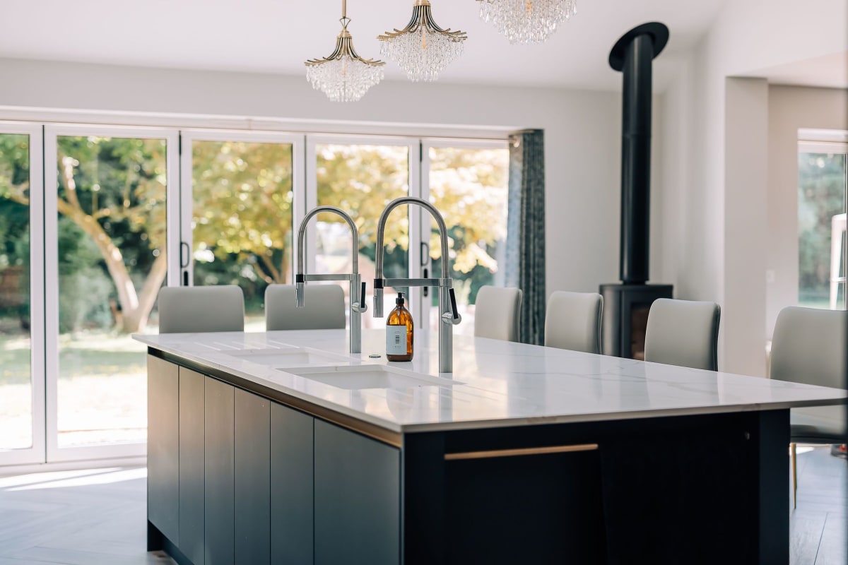 A dark blue kitchen island with white marbled quartz worktops