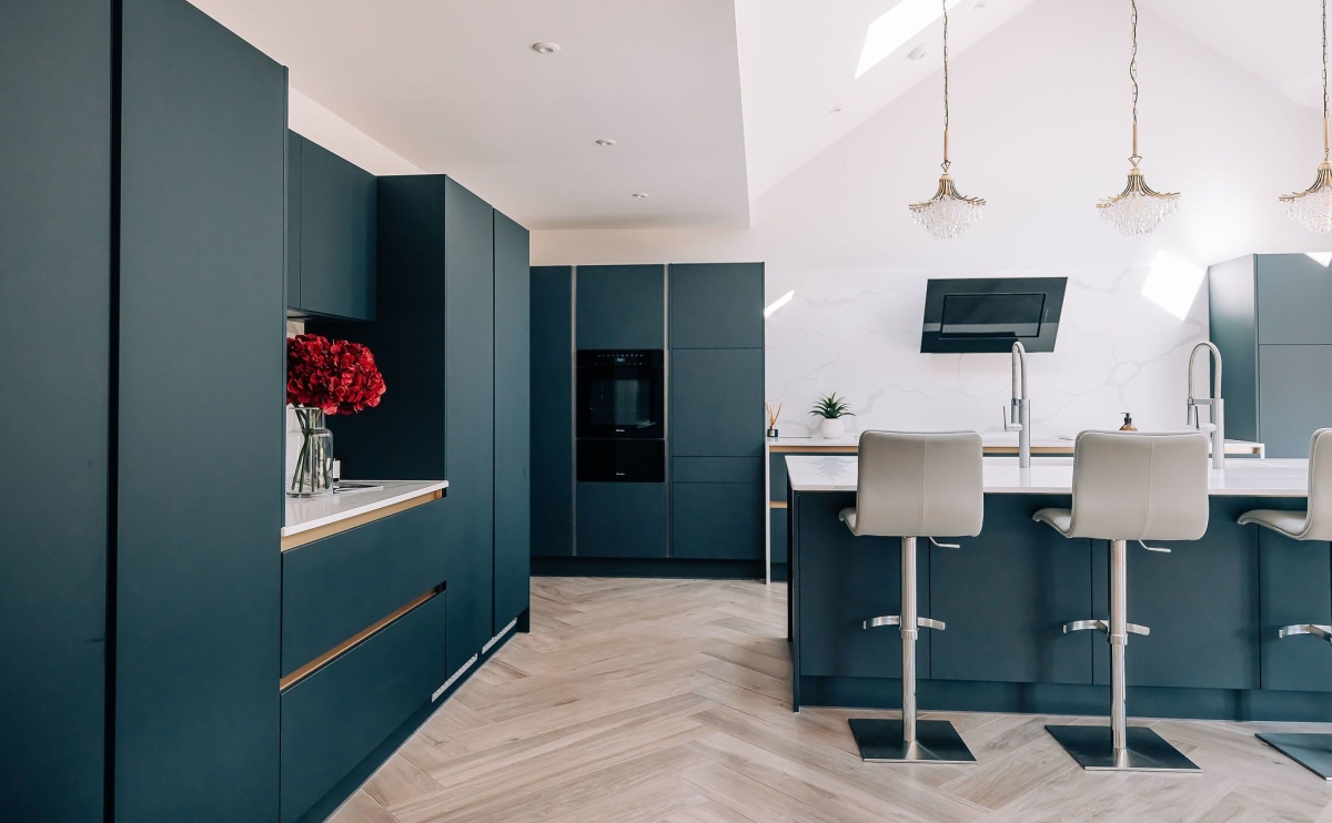 A Blue kitchen with white quartz worktop, bar stools and handleless units