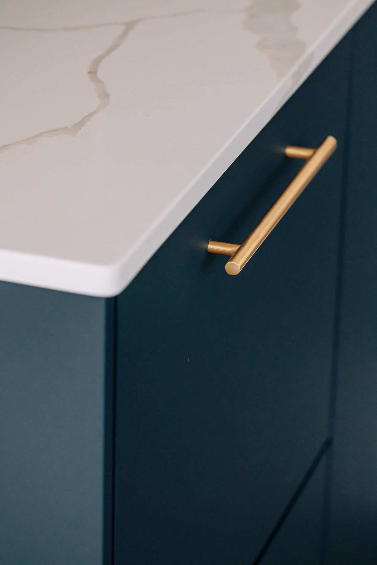 Brass Handle on a dark blue drawer with a white quartz worktop above it