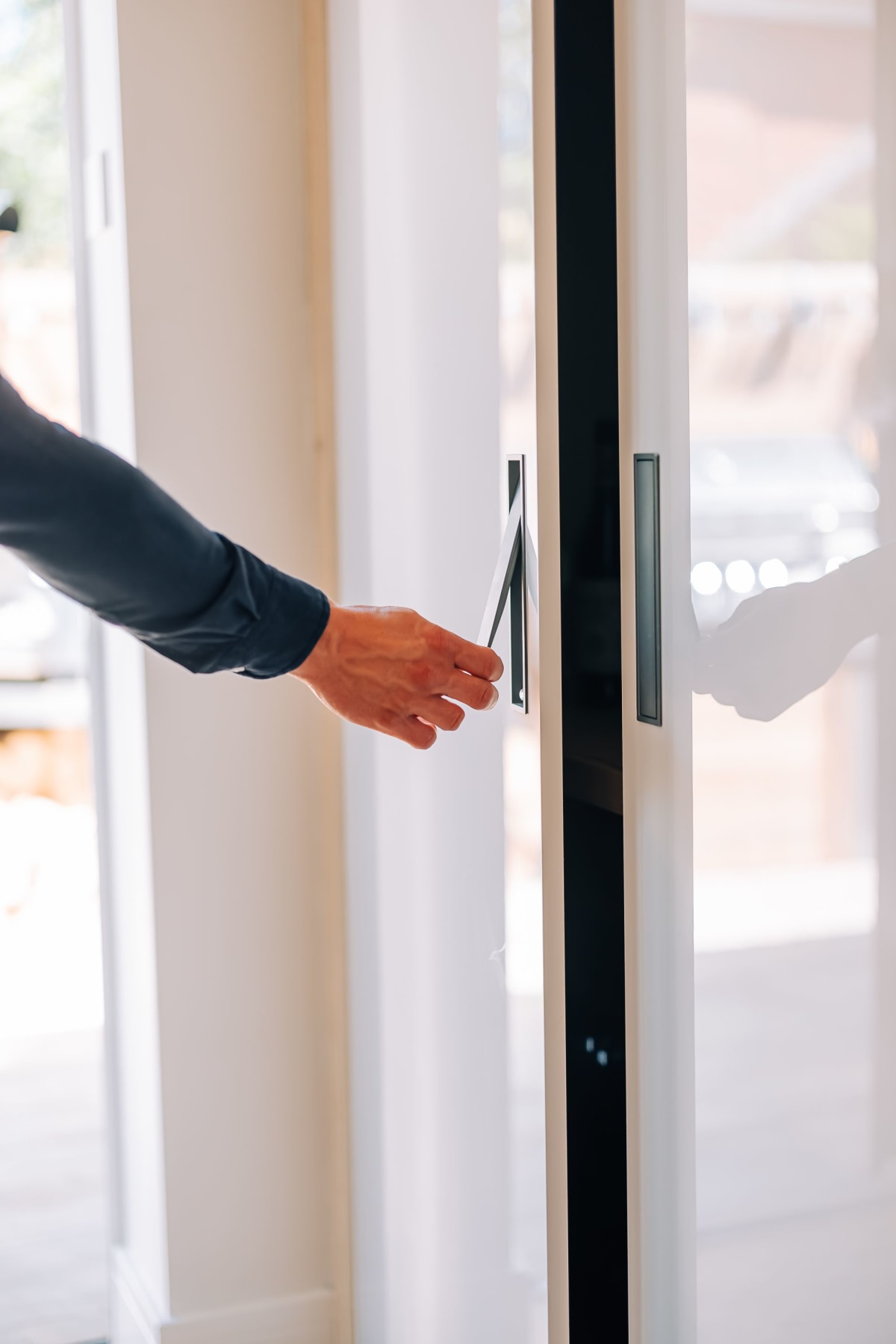 a hand opening a pocket door bar with white gloss doors