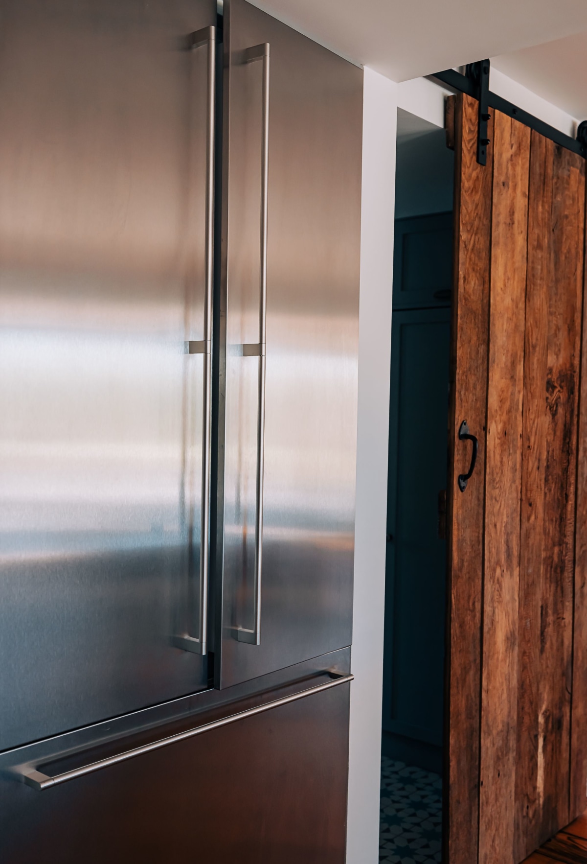 A Large Stainless Steel Fridge Freezer stand beside an antique wooden sliding door