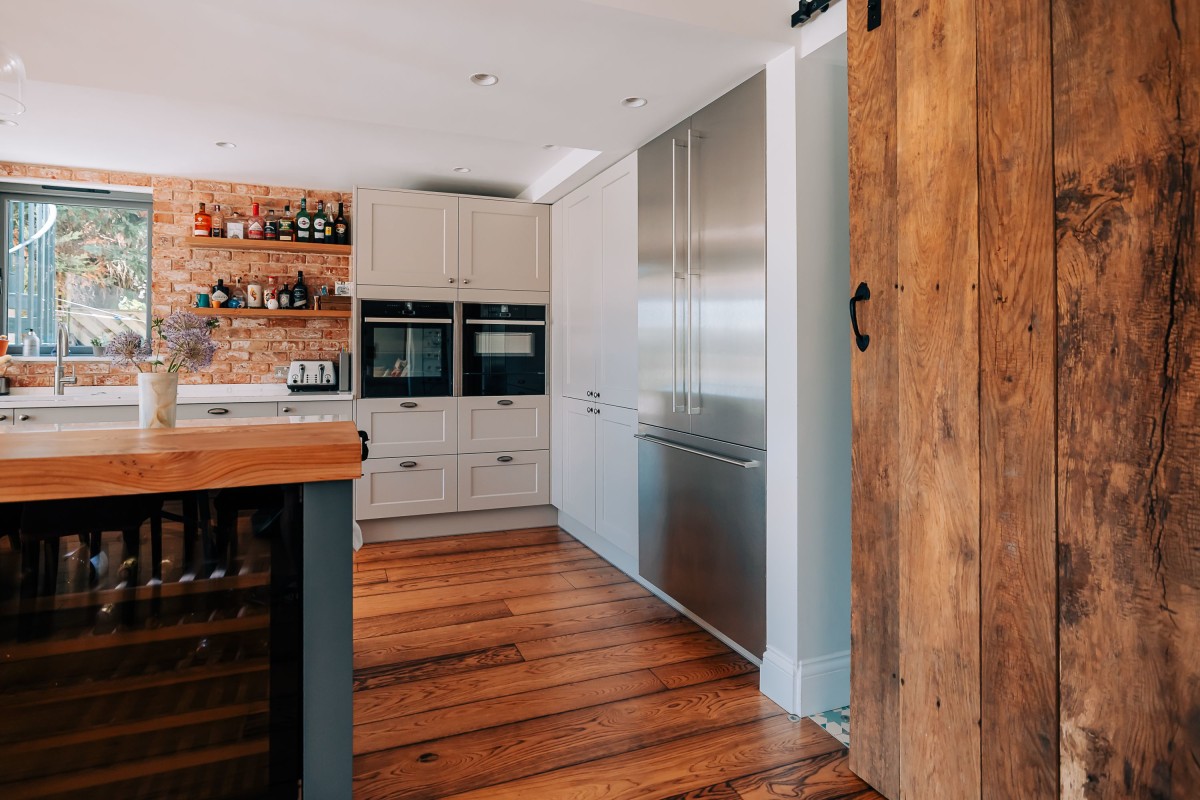 A Kitchen island, kitchen units, stainless steel Gaggenau Firdge Freezer and wooden door