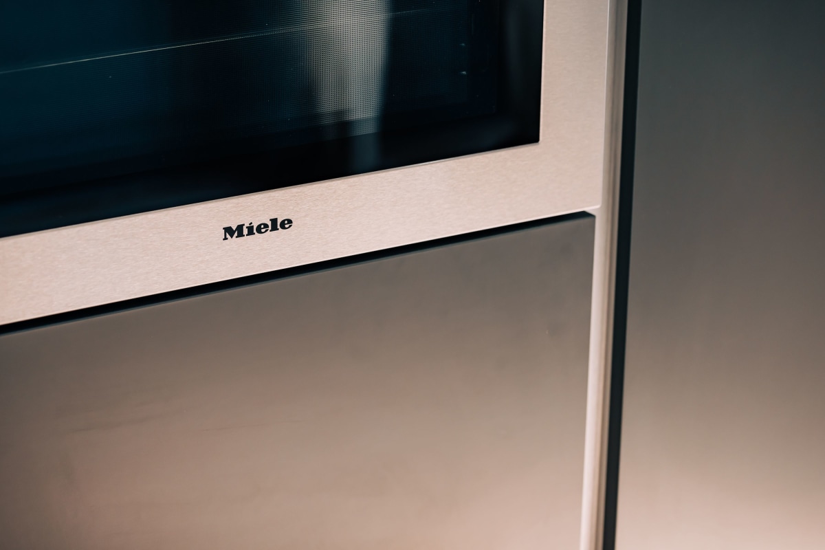 A stainless steel miele oven built in to dark blue kitchen cabinetry