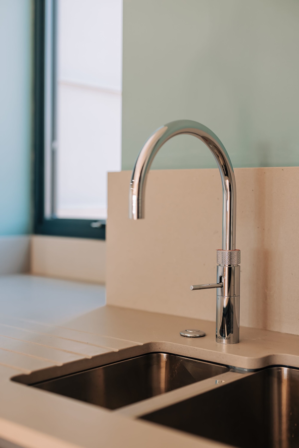 A Quooker Fusion tap above a stainless steel sink inset in a quartz worktop