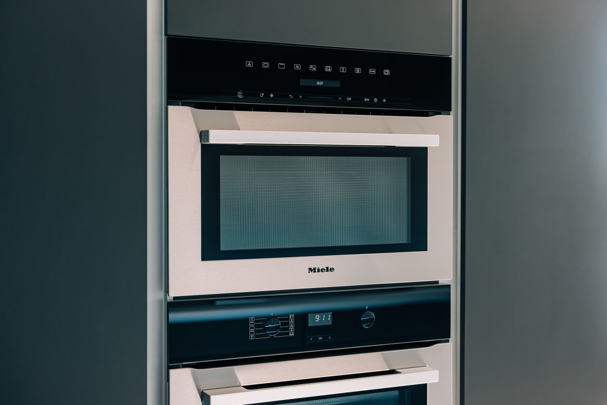 A stainless steel Miele double oven with dark blue Mereway cabinetry around it