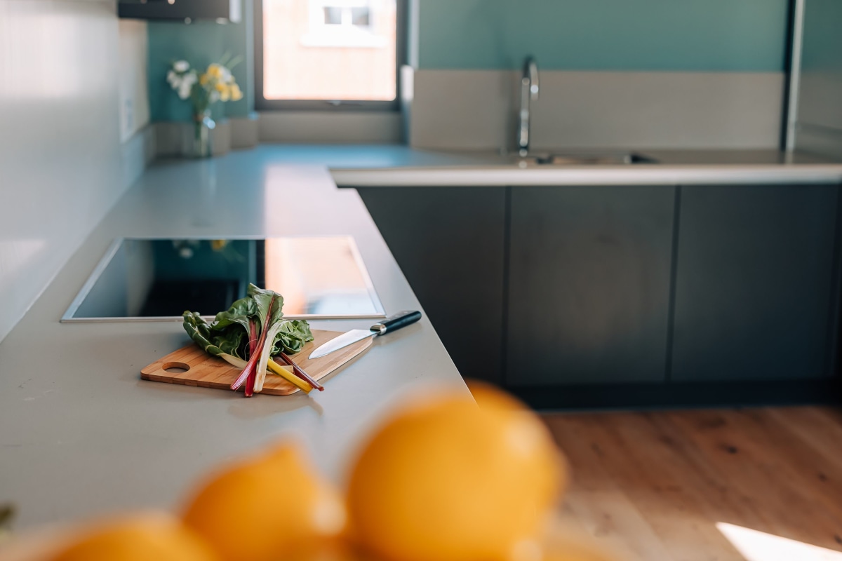 A bowl of oranges on a quartz worktop with a chopping board in the background in a modern kitchen