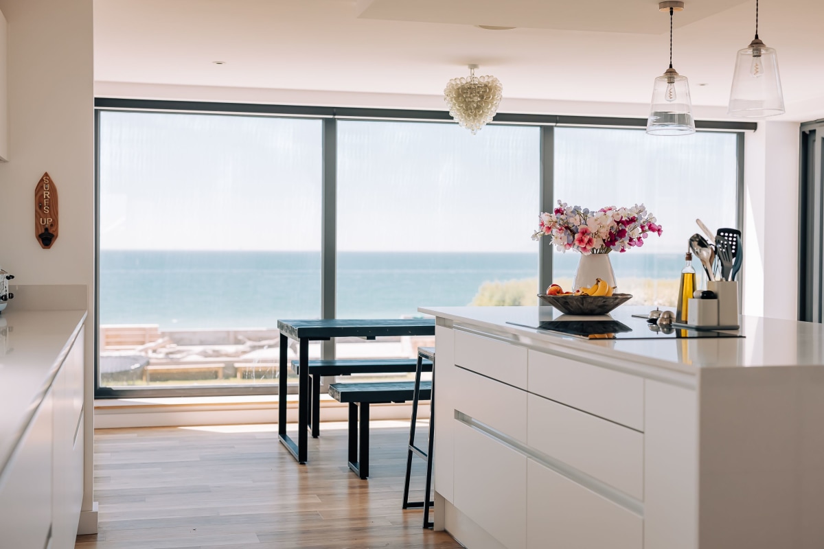 View across a white quartz counter top to a backdrop of the beach in a Modern style kitchen