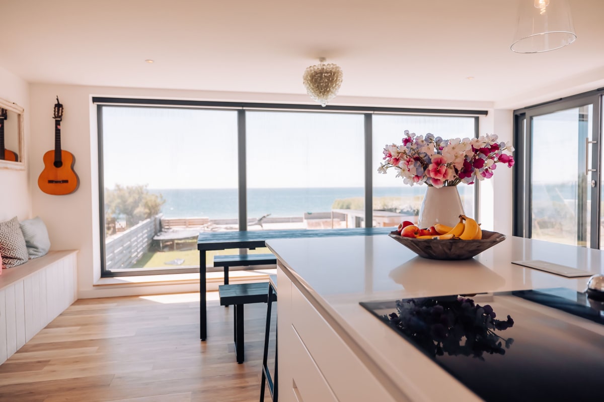 A kitchen Island looking out to a large picture window showing Witterings beach