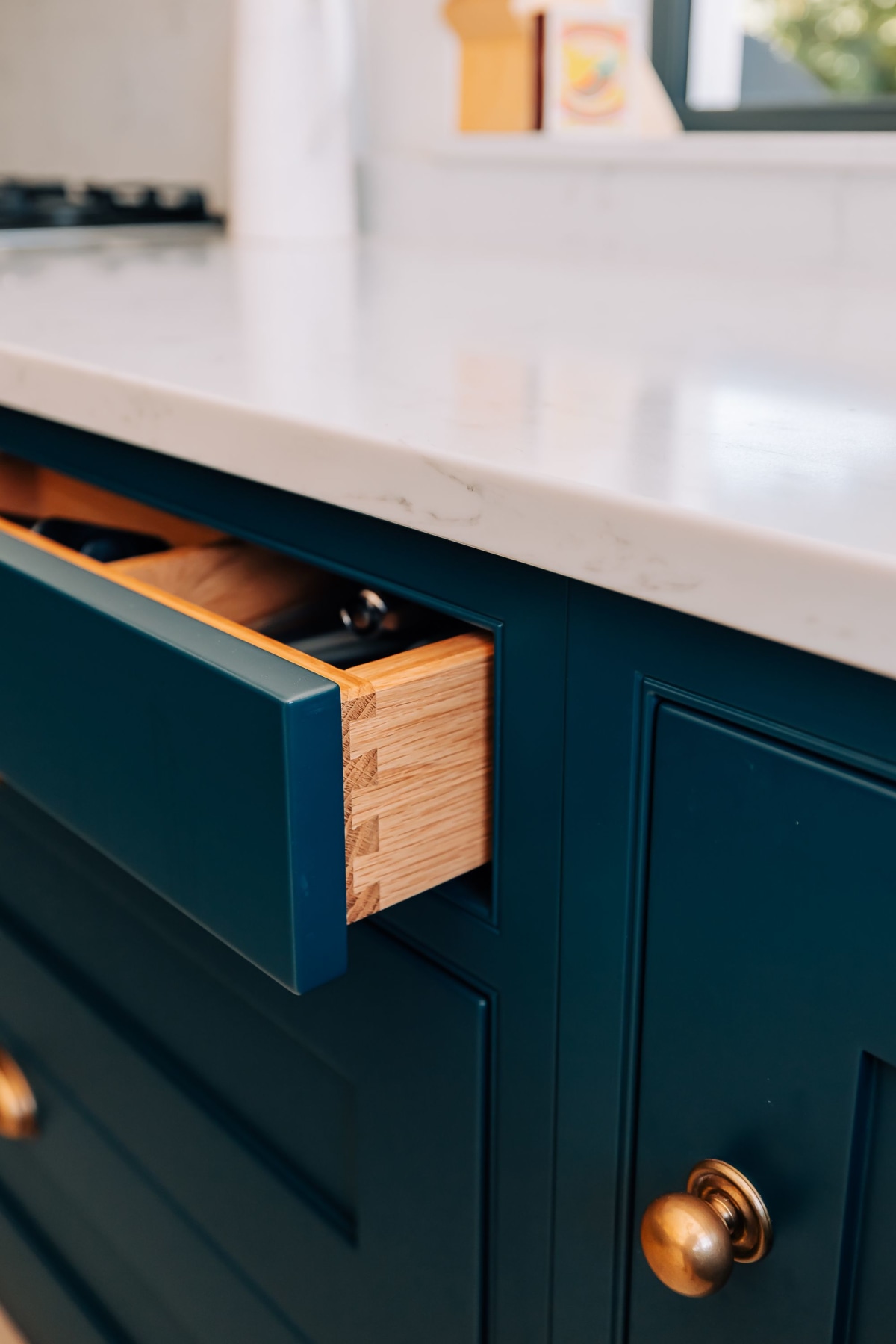 An oak drawer with Azure Blue cabinetry surrounding it