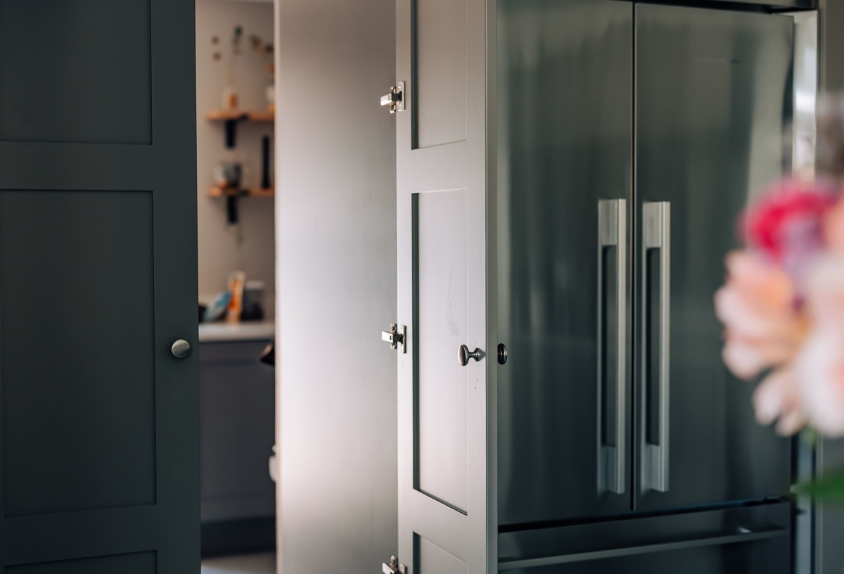 A shaker door opening on to a utility room with an american fridge freezer to the right side