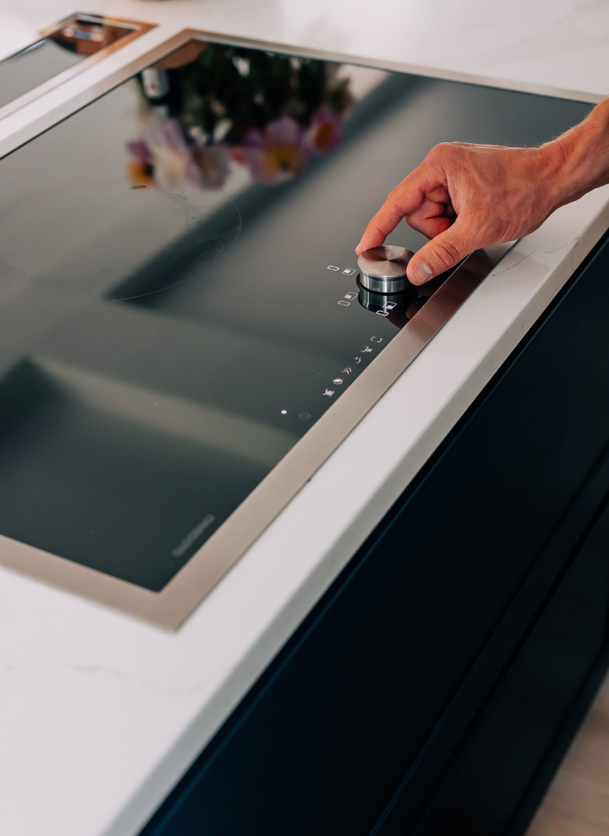 A Gaggenau induction hob with Stainless Steel trim being operated by a hand