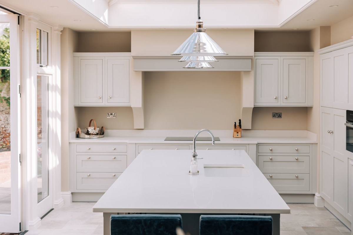 A pale coloiured shaker kitchen with white quartz worktops