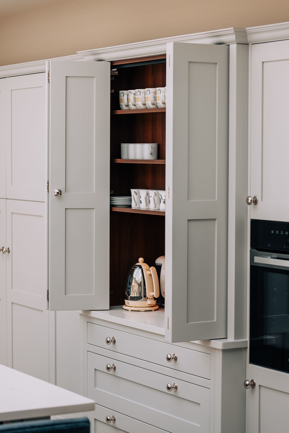 An open, light coloured kitchen cupboard with oak inlay