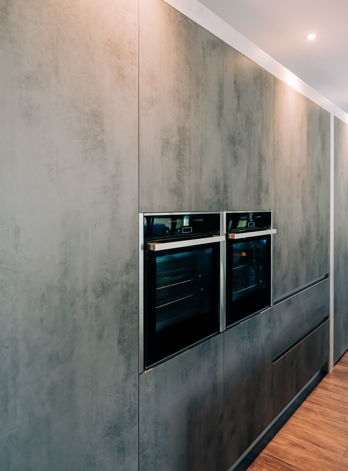 Two ovens in a bank of concrete effect kitchen units