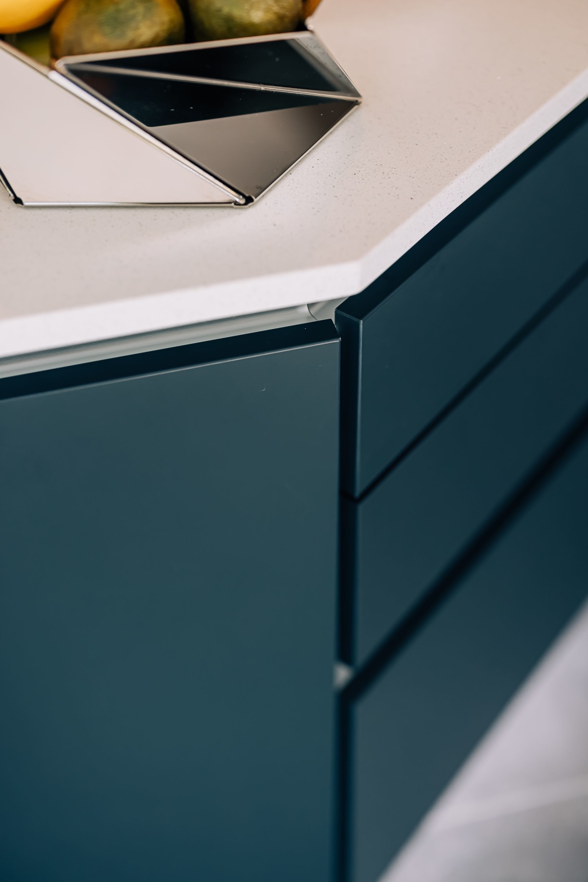 The Corner of a kitchen island with white quartz worktop and azure blue cabinetry