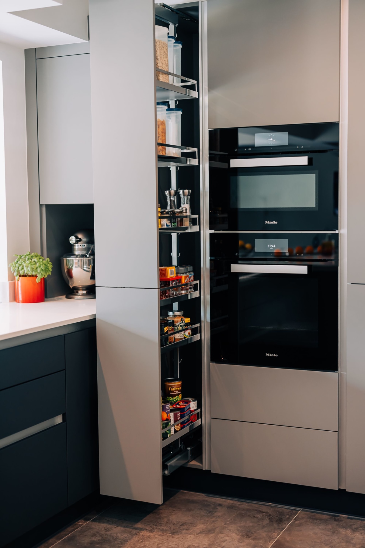 A bank of ovens with a pull out larder next to it