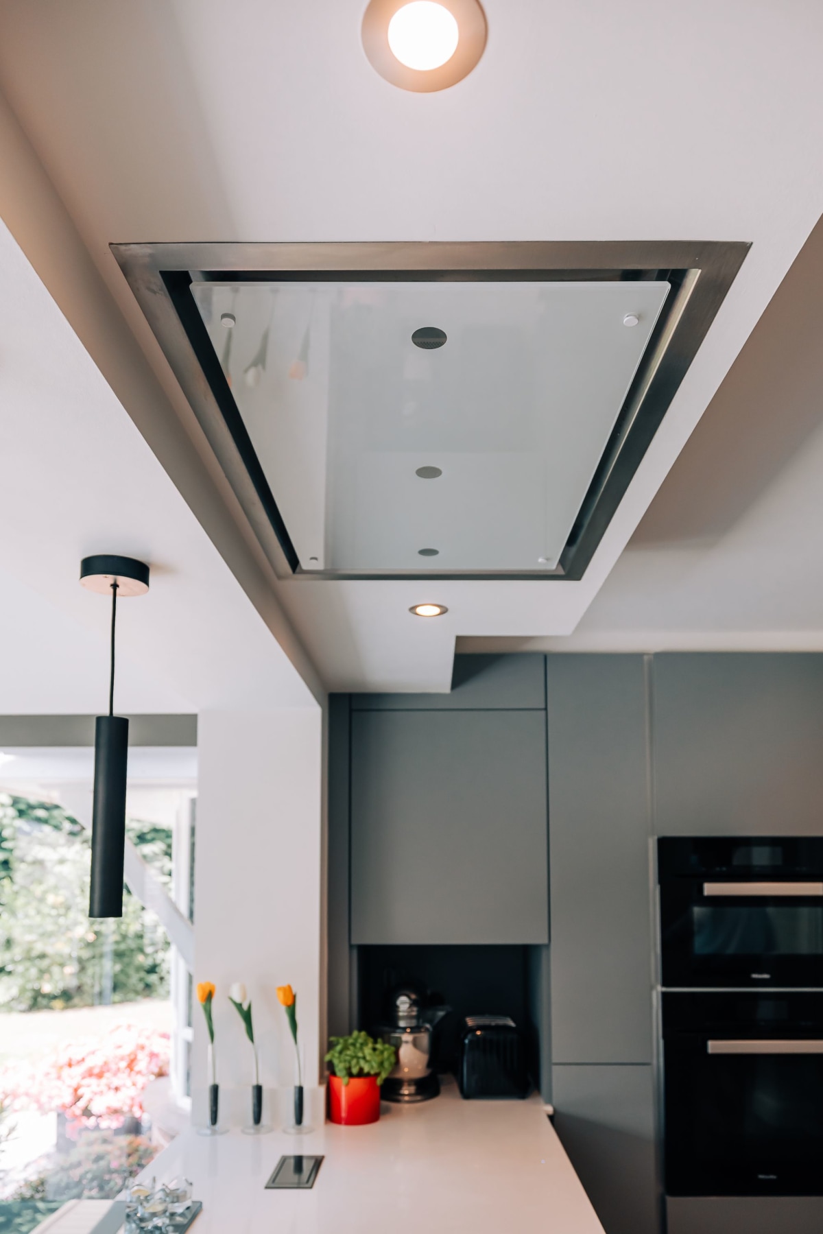 A Sylvarna Kitchens cloud box extractor in the ceiling above an induction hob in a white quartz worktop