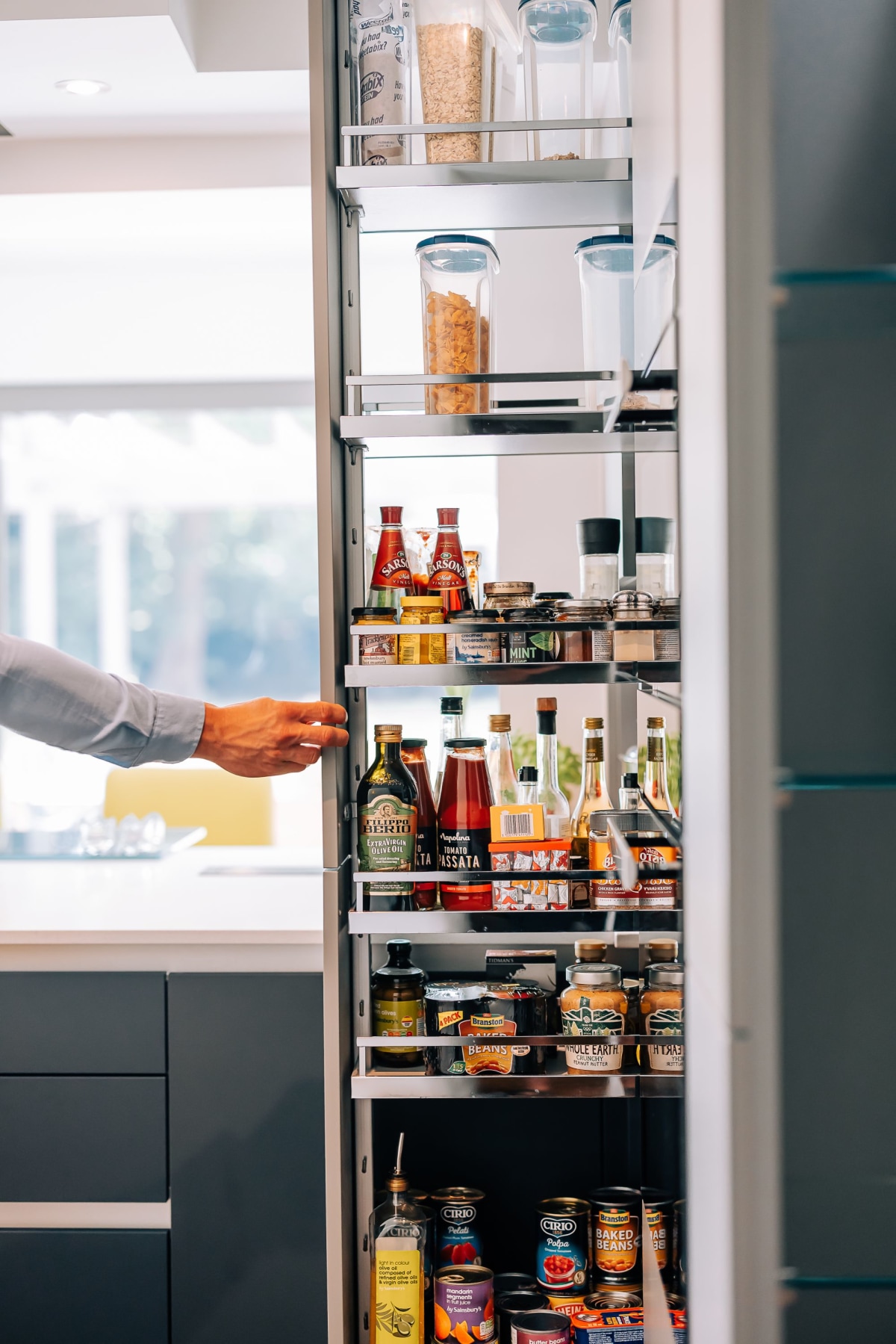 A pull out larder unit is being pulled out by a hand