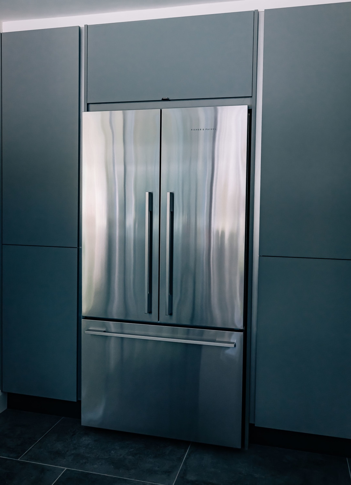 A Stainless Steel American Fridge Freezer inset into blue kitchen cabinetry