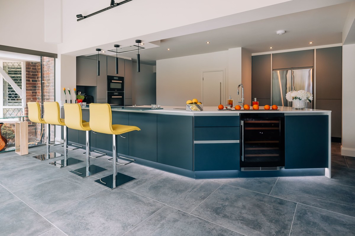 A modern kitchen with yellow bar stools and dark units.