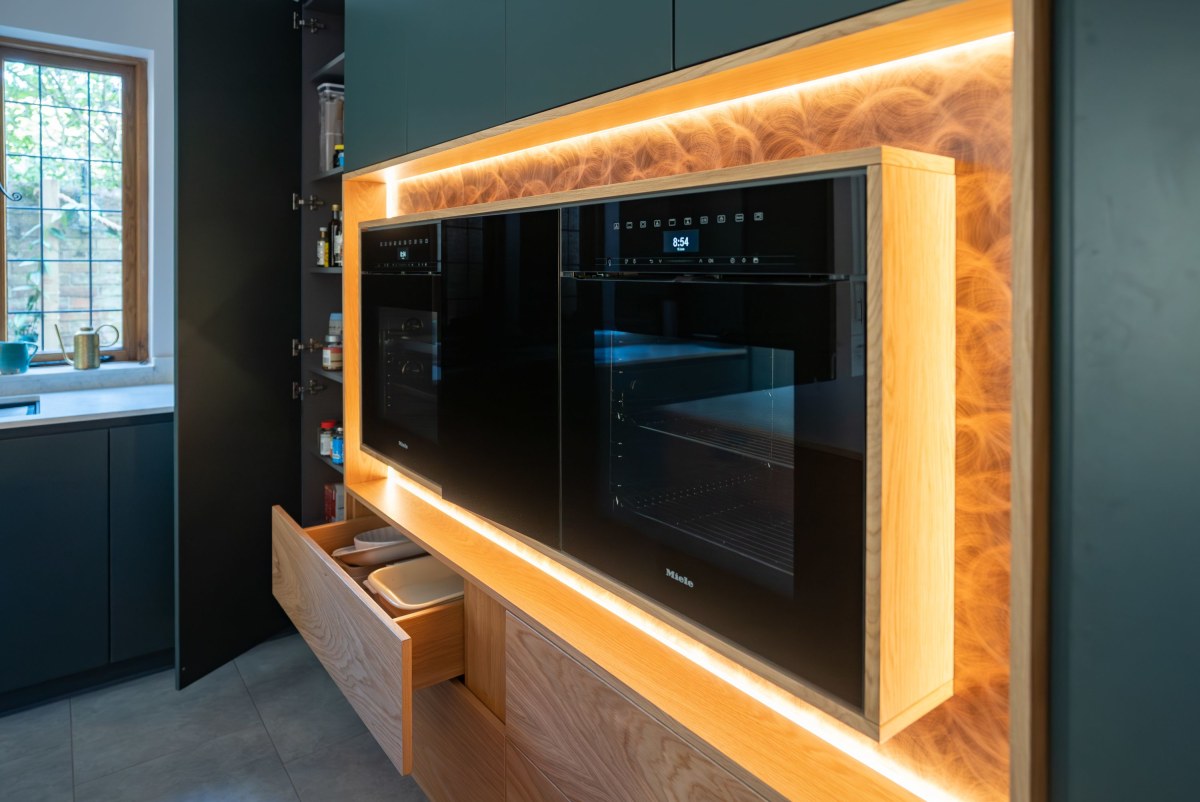 an illuminated feature oven with copper surround, lights and two black miele ovens in the centre